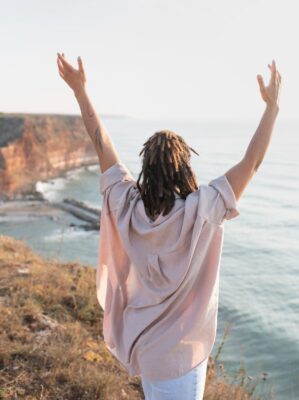 Woman on beach with hands up showing a lot of joy and freedom