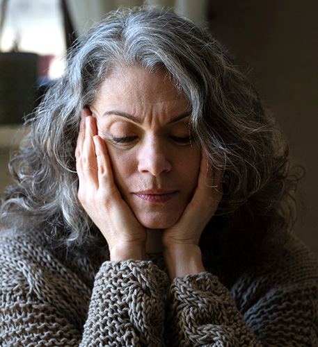 Older woman with fact in hands looking sad and concerned.