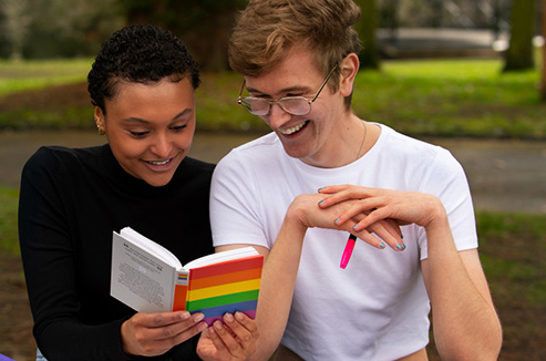 Two people reading and discussing content in an LGBTQIA+ book