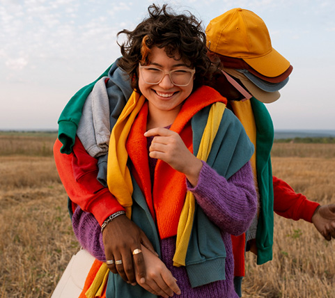 Man and woman wearing colorful clothes playing in a field and experiencing joy.
